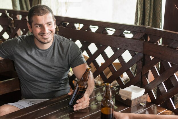 Vrolijke man bier drinken met vriend in bar