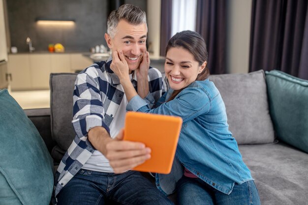 Vrolijke man en ontroerende vrouw die selfie op tablet nemen