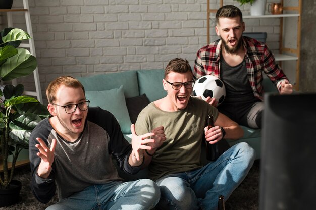 Vrolijke mannelijke vrienden kijken naar sport op tv met voetbal