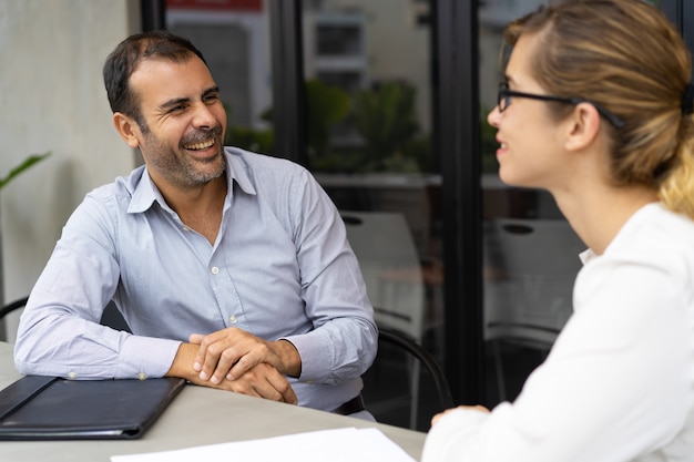 Gratis foto vrolijke medio volwassen hr manager die gesprek met kandidaat heeft