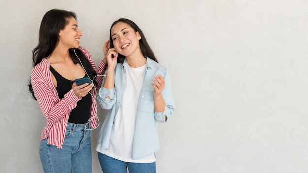 Gratis foto vrolijke meisjes die aan muziek in hoofdtelefoons luisteren