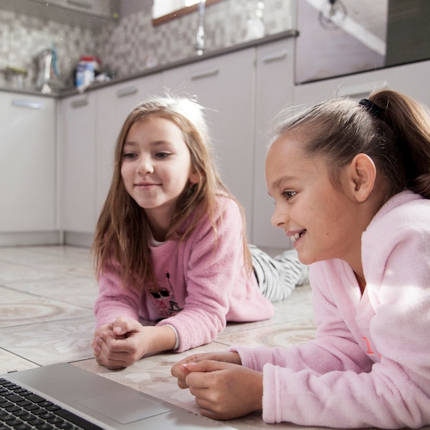 Vrolijke meisjes die op film op laptop letten