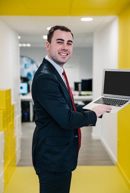 Vrolijke mens die laptop in bureau met behulp van