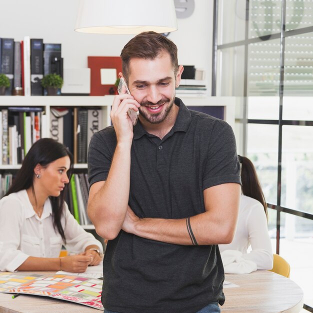 Vrolijke mens die op smartphone in bureau spreekt