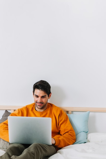 Vrolijke mens het doorbladeren laptop op bed