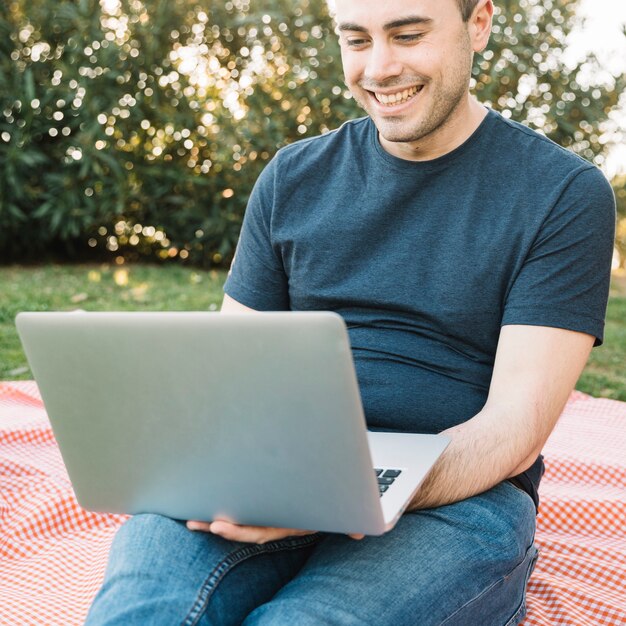 Vrolijke mens het doorbladeren laptop op picknick