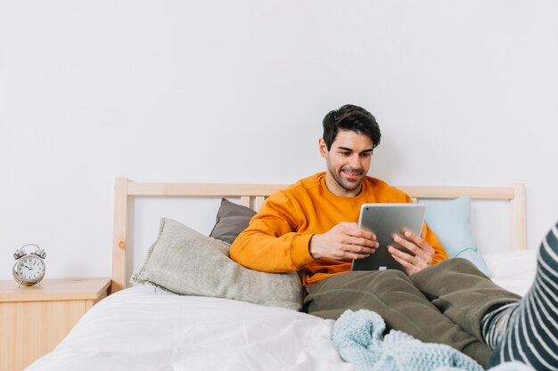 Vrolijke mens het doorbladeren tablet op bed