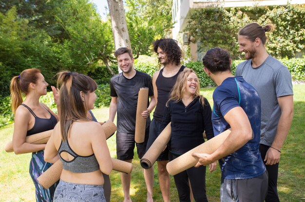 Vrolijke mensen met yoga matten chatten en lachen