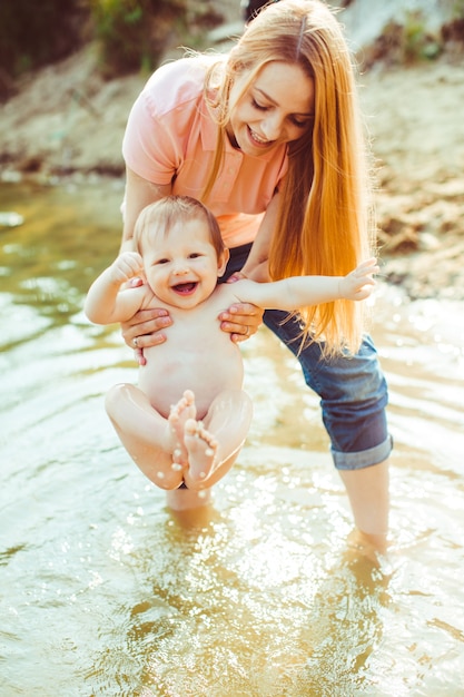 Gratis foto vrolijke moeder houdt een naakte baby in haar armen