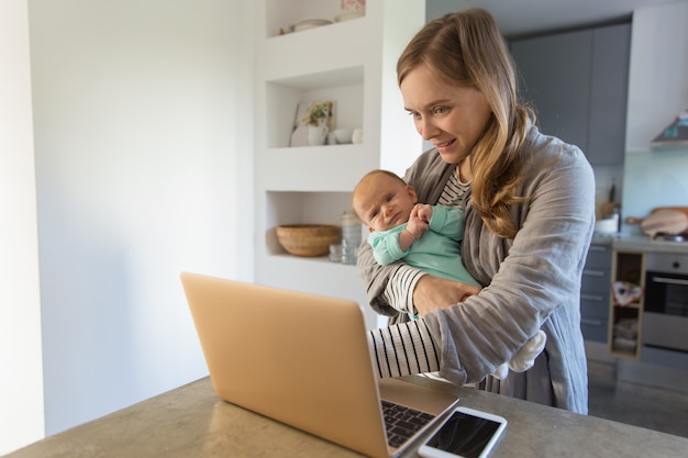 Gratis foto vrolijke nieuwe moeder rockende baby