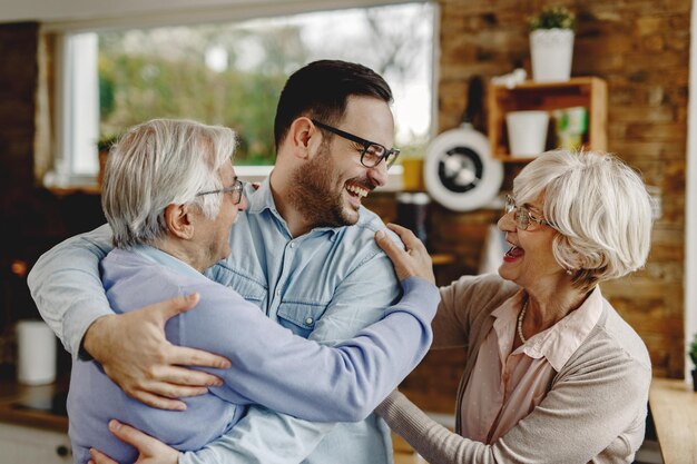 Vrolijke oudere ouders die plezier hebben tijdens het begroeten met hun zoon die hen kwam bezoeken