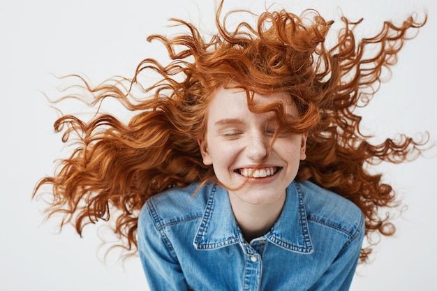 vrolijke roodharige vrouw met krullend haar glimlachend glimlachen lachen met gesloten ogen.