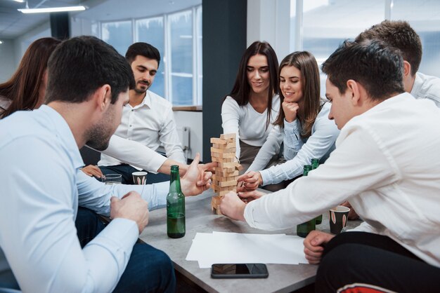 Vrolijke sfeer. Succesvolle deal vieren. Jonge beambten die dichtbij de lijst met alcohol zitten