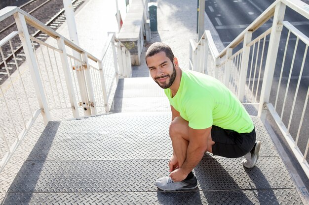 Vrolijke sportman koppelen schoenveters op sneakers