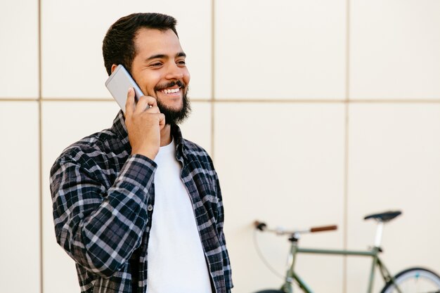 Vrolijke stijlvolle jonge bebaarde man communiceren door mobiele telefoon