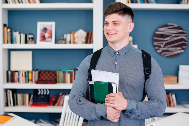 Vrolijke student met leerboek en notebook