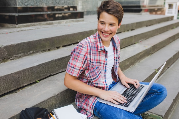 Gratis foto vrolijke student poseren met laptop