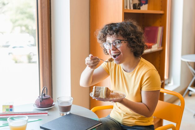 Vrolijke tiener die dessert in bibliotheek eet