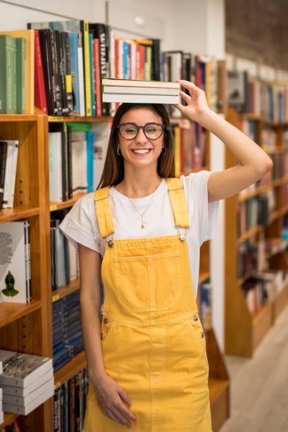 Vrolijke tiener schoolmeisje bedrijf boeken op het hoofd