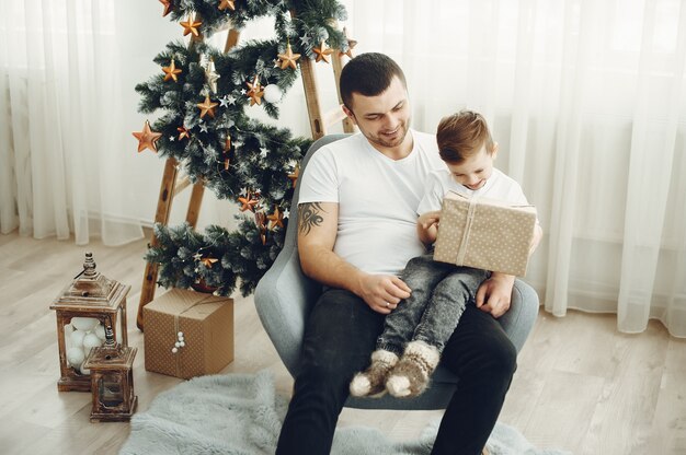 Vrolijke vader en zoon zitten in de buurt van kerstversiering. De jongen zit van vreugde