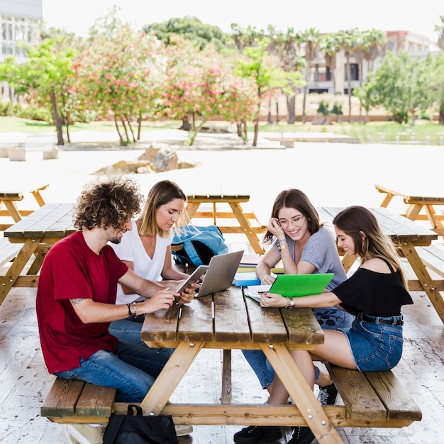 Vrolijke vrienden die aan tafel studeren