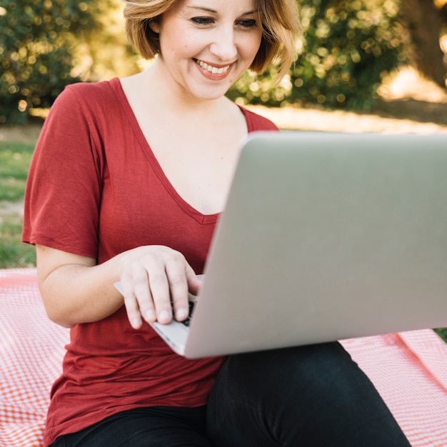 Vrolijke vrouw browsing laptop op picknick