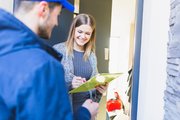 Vrolijke vrouw die document na levering ondertekent