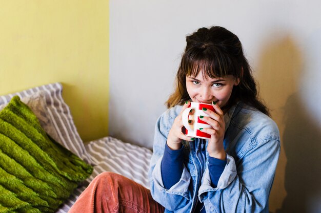 Vrolijke vrouw die op bed heeft drinken