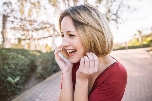 Vrolijke vrouw die op telefoon spreekt