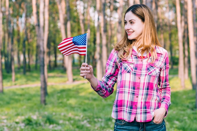 Vrolijke vrouw die zich met Amerikaanse vlag bevindt