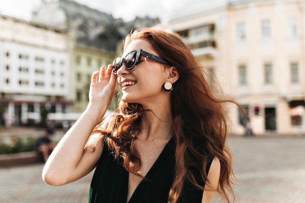 Vrolijke vrouw in trendy zonnebril lacht buiten