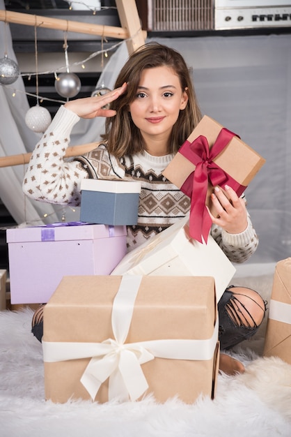 Vrolijke vrouw met een kerstcadeau in de woonkamer. H