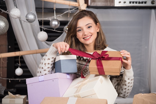 Vrolijke vrouw met een kerstcadeau in de woonkamer.