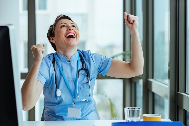 Vrolijke vrouwelijke arts die goed nieuws viert terwijl hij in het ziekenhuis werkt