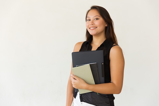 Vrolijke vrouwelijke student met map en handboeken