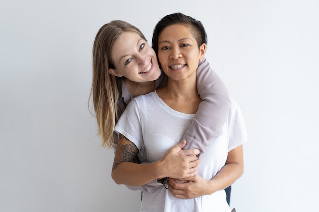 Vrolijke vrouwen die en camera omhelzen bekijken