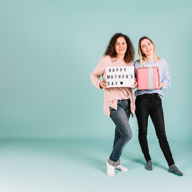 Vrolijke vrouwen met cadeau en schrijven op Moederdag