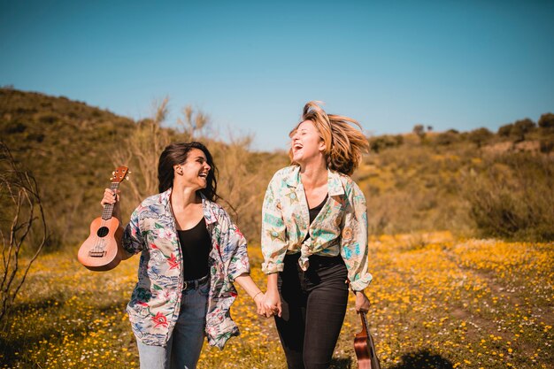 Vrolijke vrouwen met ukeleles die op gebied lopen