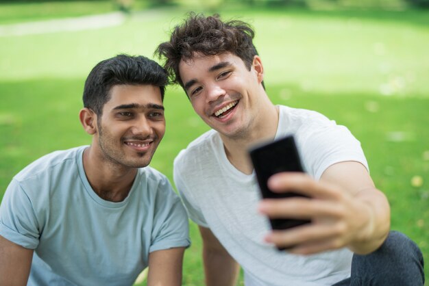 Vrolijke zorgeloze jonge mannen nemen selfie op telefoon