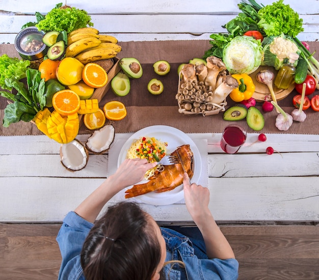 Vrouw aan de eettafel met een verscheidenheid aan biologische gezonde voeding, bovenaanzicht. Het concept van gezond eten en feest