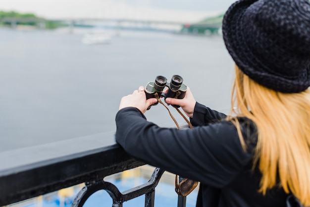 Vrouw aan de waterkant met een verrekijker