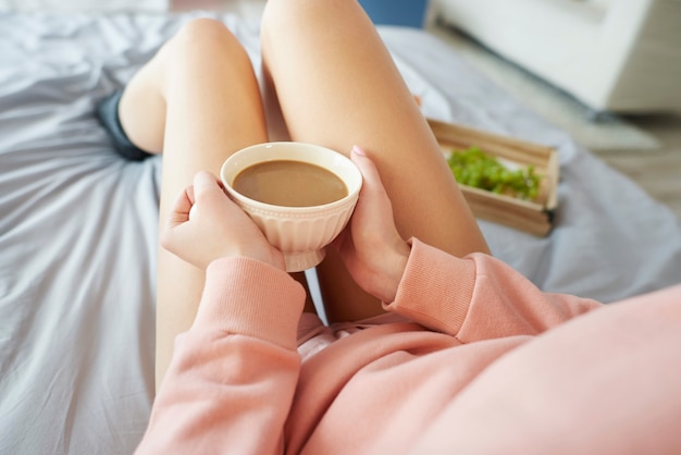 Vrouw aan het opwarmen met een kopje koffie in de ochtend