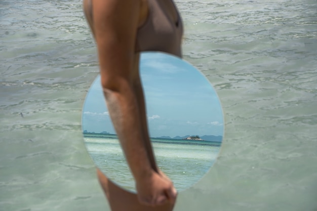 Vrouw aan het strand in de zomer poseren met ronde spiegel