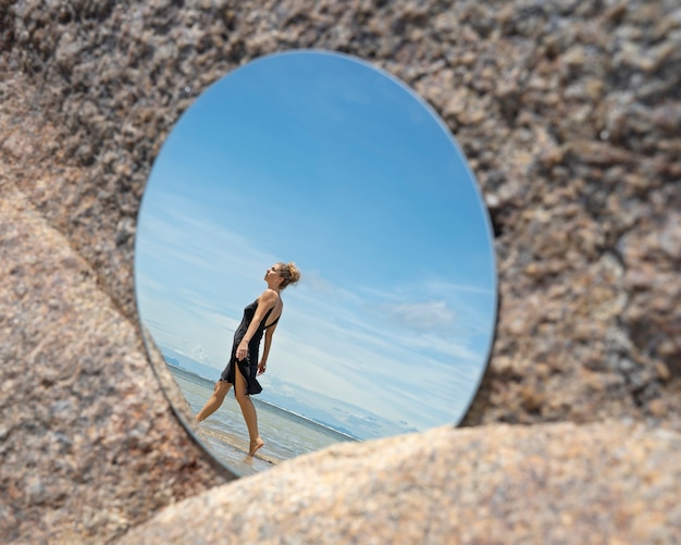 Vrouw aan het strand in de zomer poseren met ronde spiegel