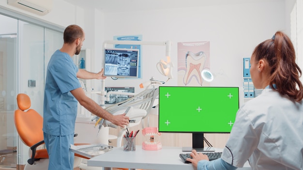 Vrouw aan het werk als tandarts met groen scherm op monitor