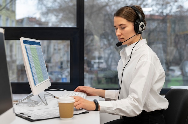 Vrouw aan het werk in callcenter kantoor met koptelefoon en computer