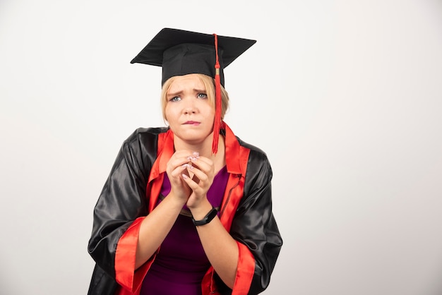 Vrouw afgestudeerde student in toga staande op wit.