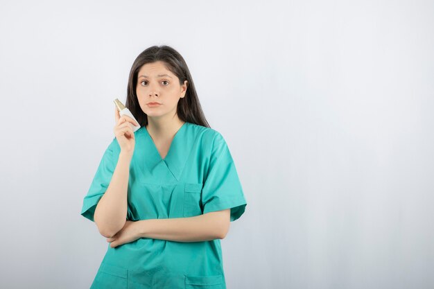Vrouw arts dragen groene uniforme bedrijf spuit op wit.