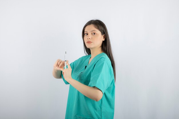 Vrouw arts dragen groene uniforme bedrijf spuit op wit.