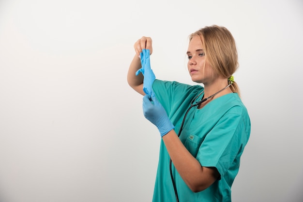 Vrouw arts in uniform kijken op latex handschoenen.